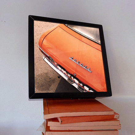 Moldura de luz com a imagem da mitica traseira da Toyota. Carro laranja, livros laranjas.